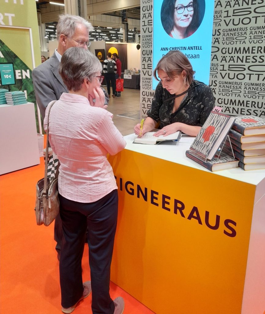 Jenni Räinä signeeraa teostaan.